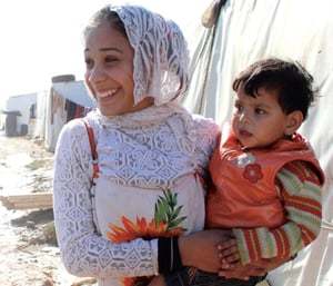 A young Syrian refugee holds her baby sister in an informal settlement in Lebanon's Bekaa Valley- Information Cropped-2